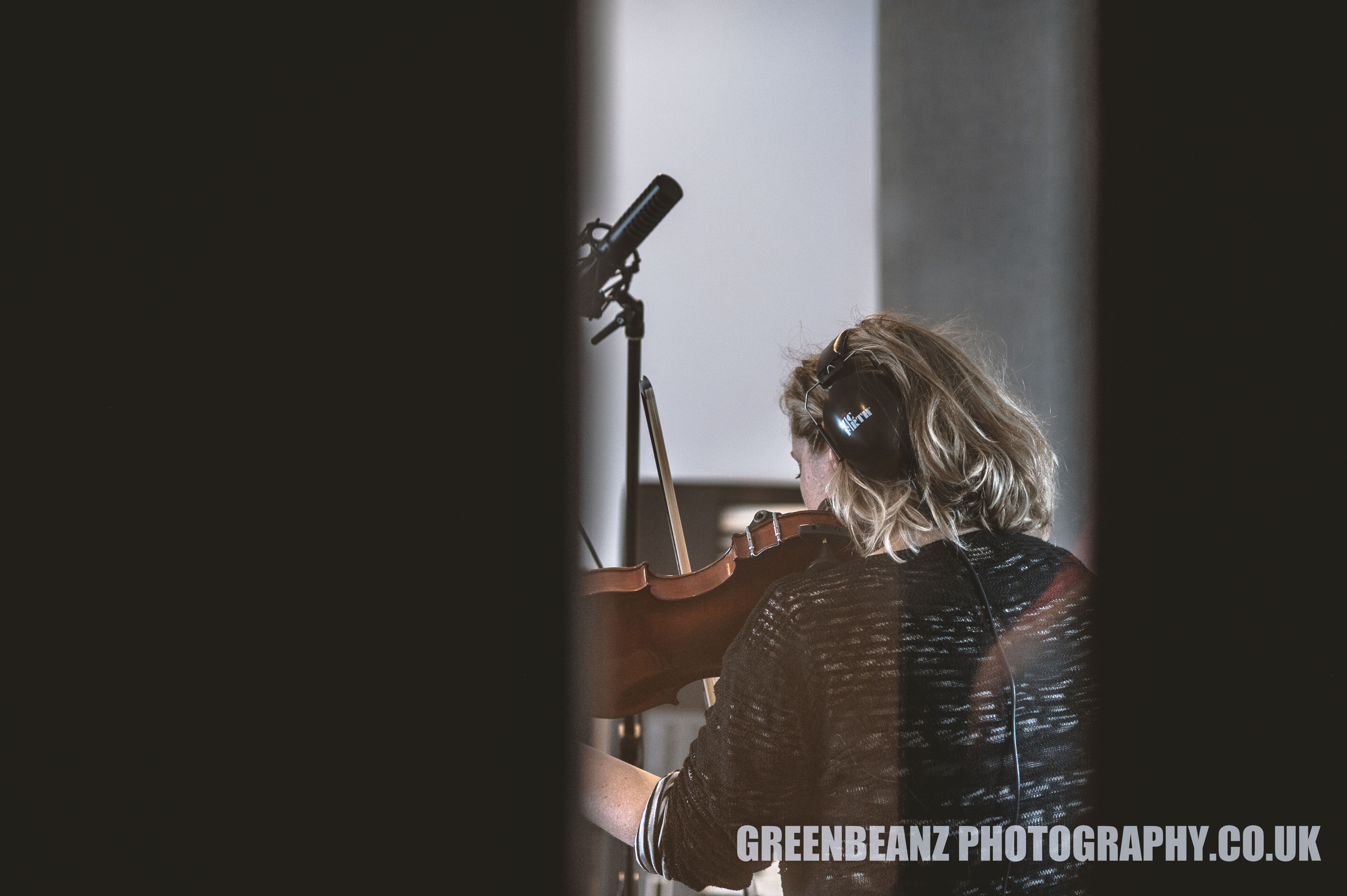 Image of Violinist Sam Spake thru recording studio glass door