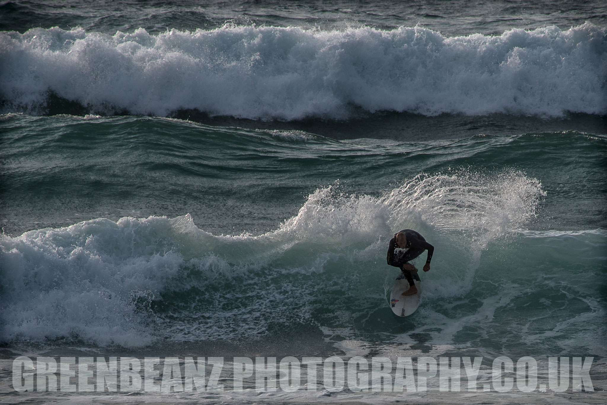 Surfer crouching on board riding a wave off the Cornish coast