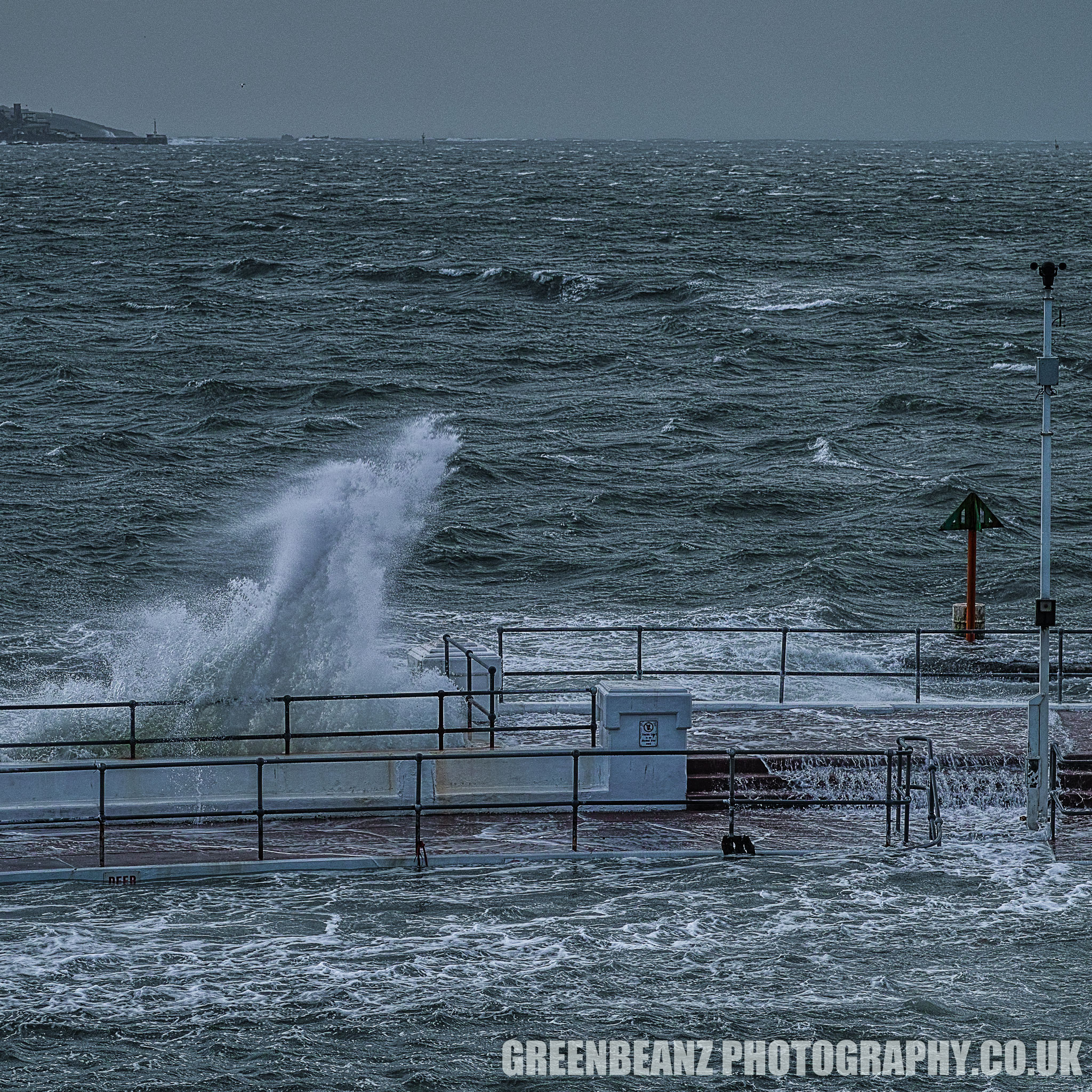 Storm Waves Plymouth Hoe. The Lido pool is buffeted and flooded by the sea