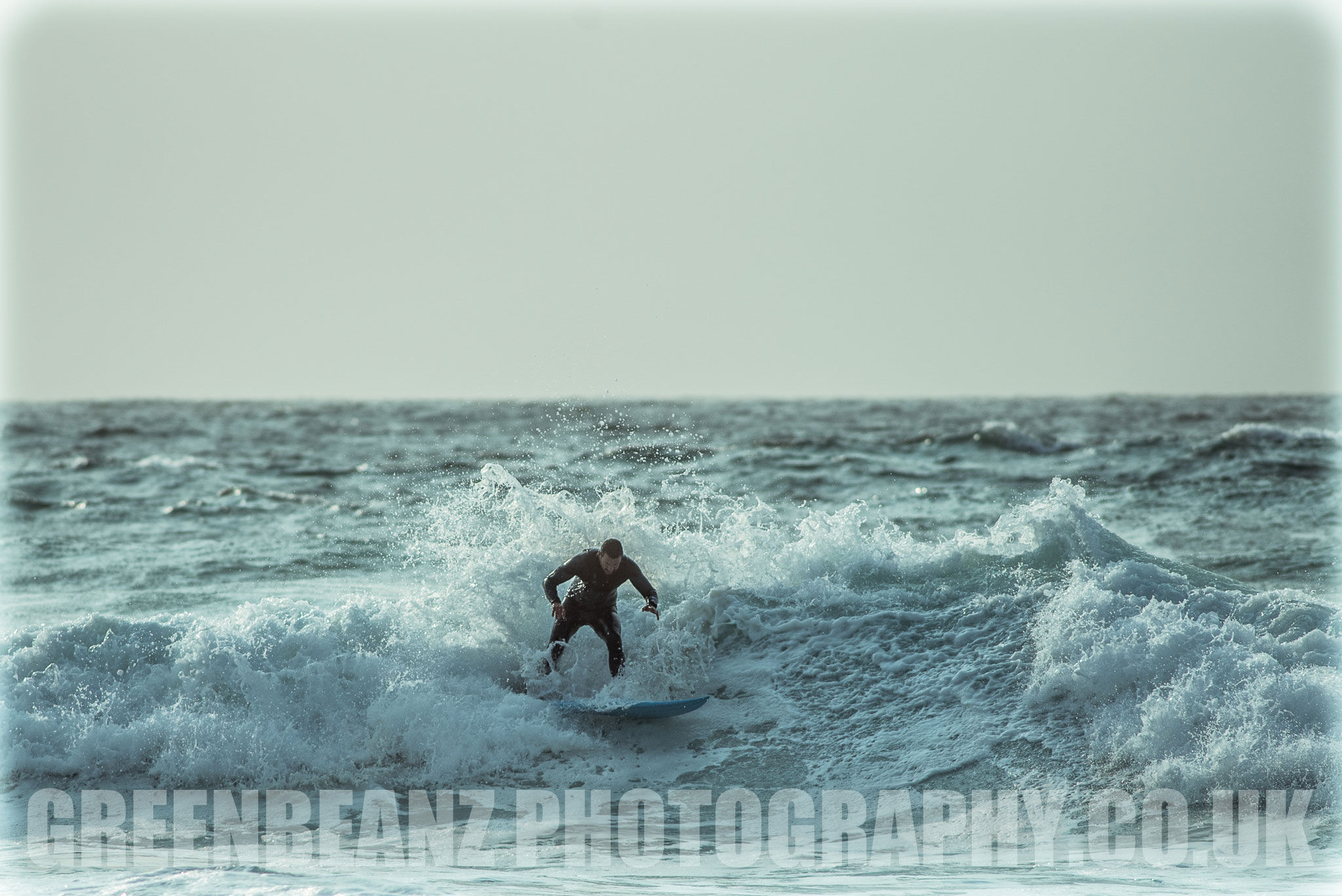 Surfer photographed with black wetsuit and white waves