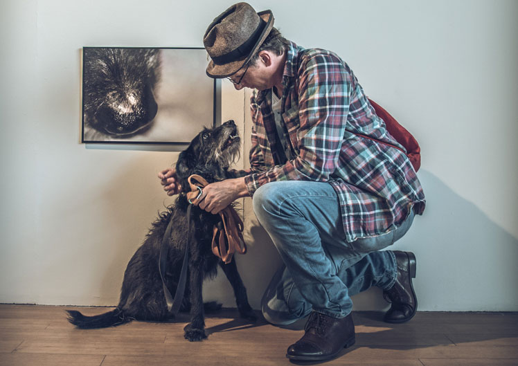 Artist Kevin Attwod with Dog Josh below photograph of dogs nose in a gallery